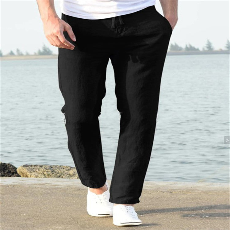 Person wearing black pants and white shoes by a body of water
