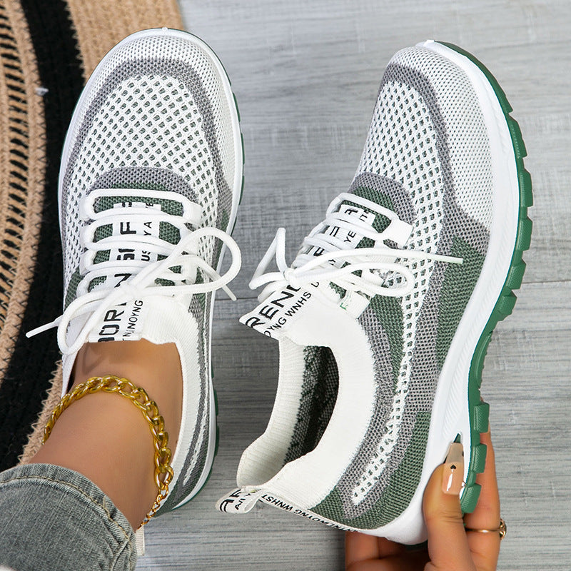 Pair of gray and green sneakers with white soles on a wooden floor.