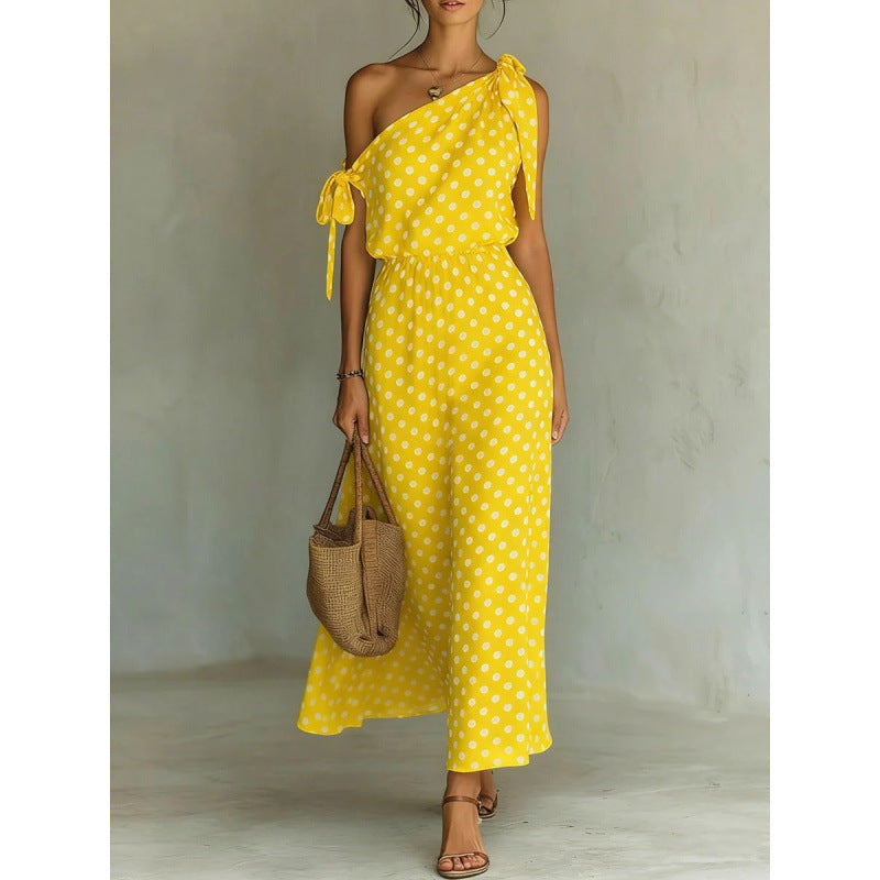 Woman wearing a yellow polka dot dress holding a woven bag against a neutral background