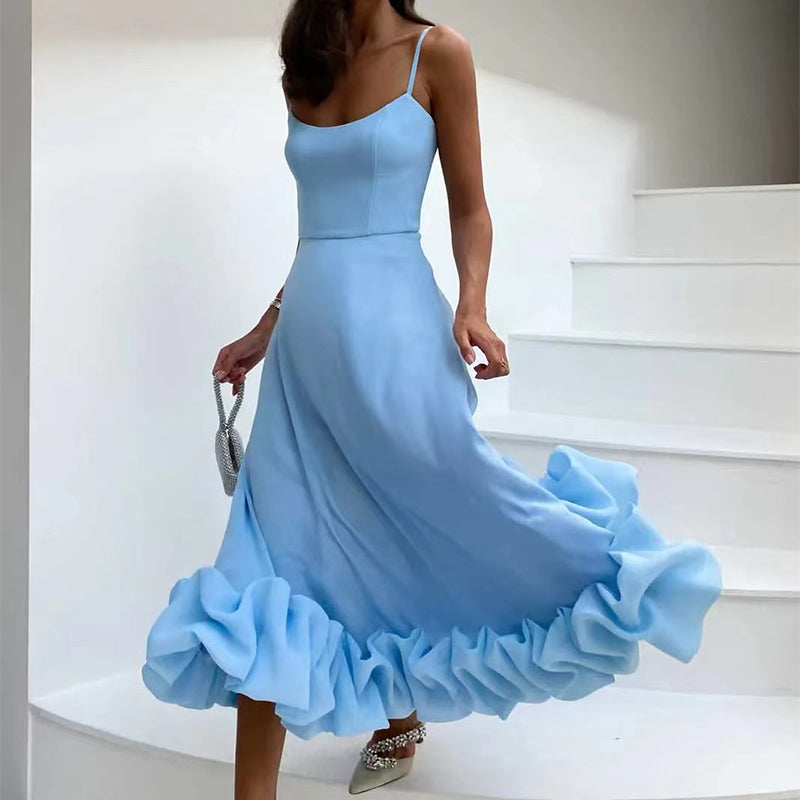 Woman wearing a light blue dress with a ruffled skirt on a white staircase.