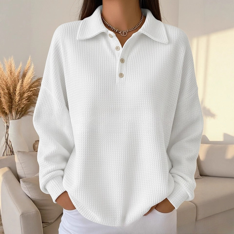 Person wearing a white ribbed sweater in a cozy living room setting