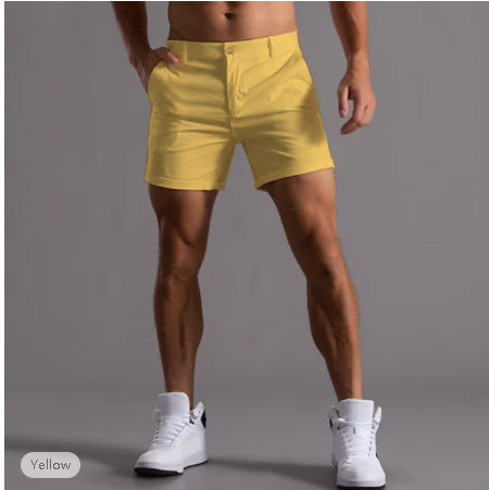 Person wearing yellow shorts and white sneakers on a gray background