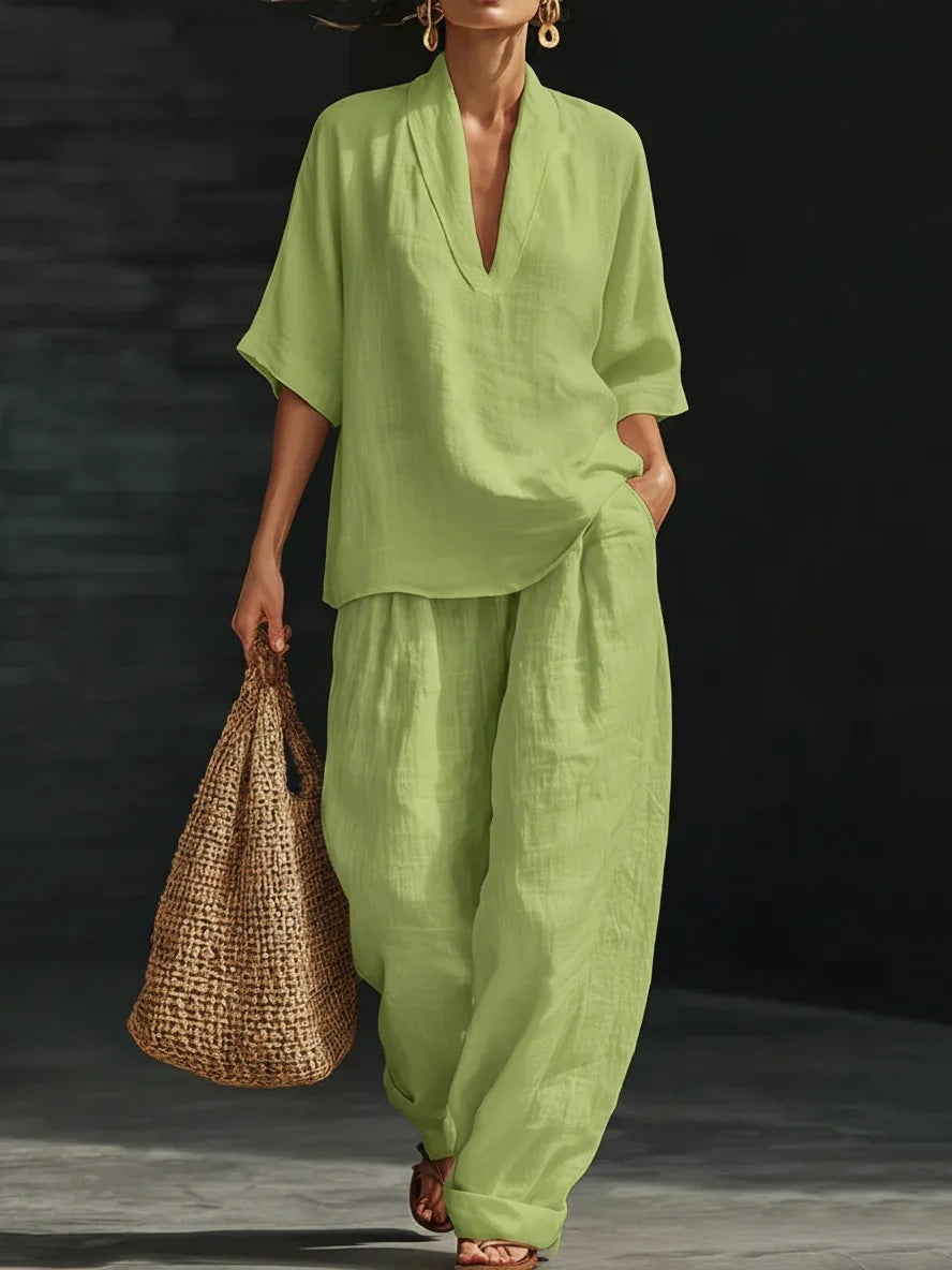 Woman wearing a light green outfit holding a woven bag against a dark background
