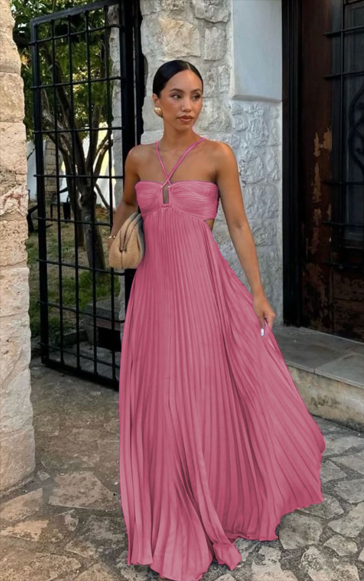 Woman in a pink dress standing outdoors near a stone building.