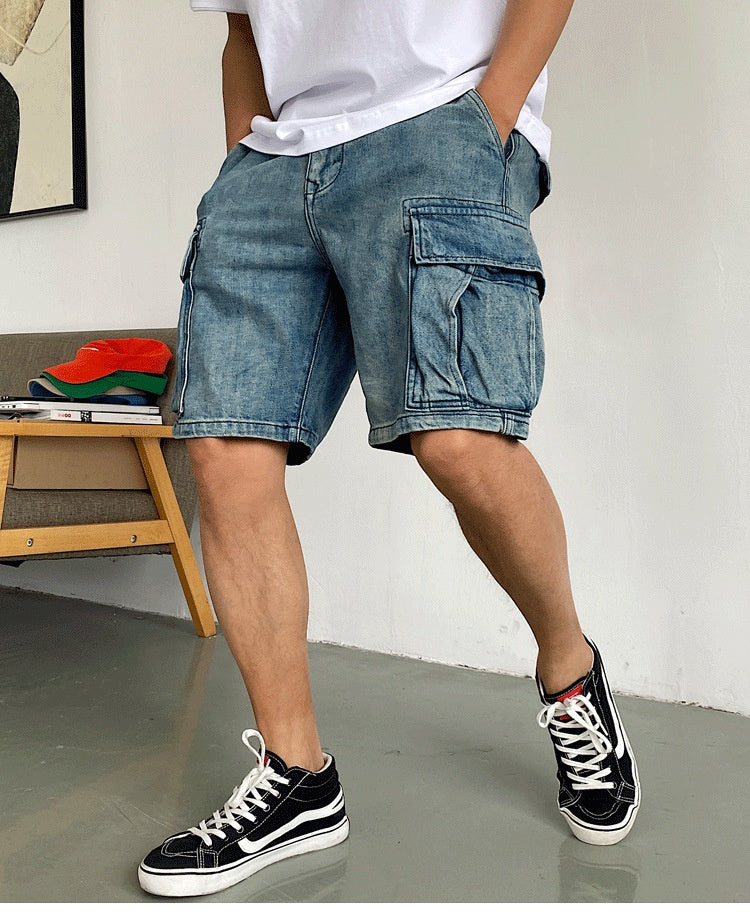Person wearing blue denim cargo shorts and black sneakers indoors.